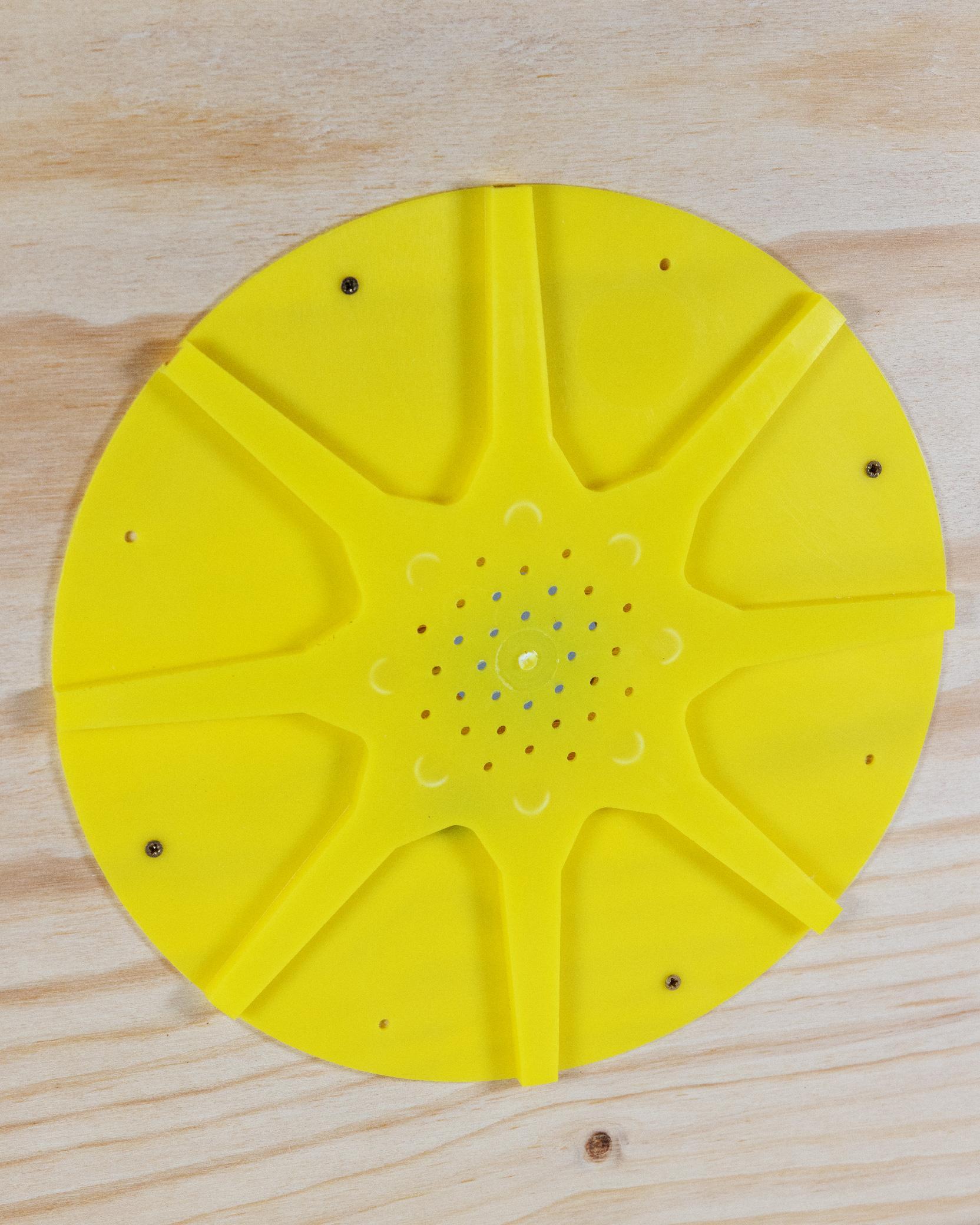 Dettaglio apiscampo a otto uscite in plastica gialla installato su tavoletta